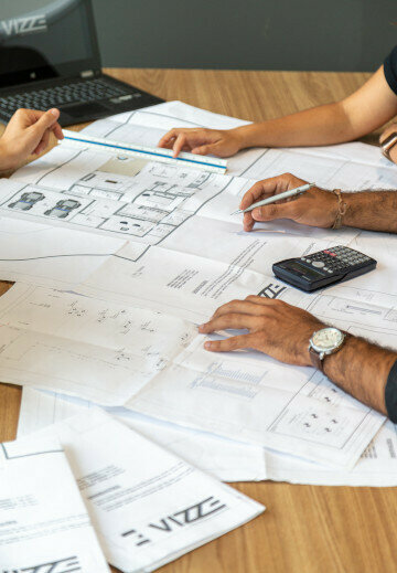 Planbesprechung mit Bauplänen als Symbol für Bauzeitenplan, Terminplanung und Koordination für Architekten und Planungsbüros